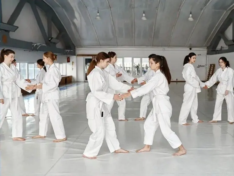 Group of students practicing partner drills in martial arts class at training hall.
