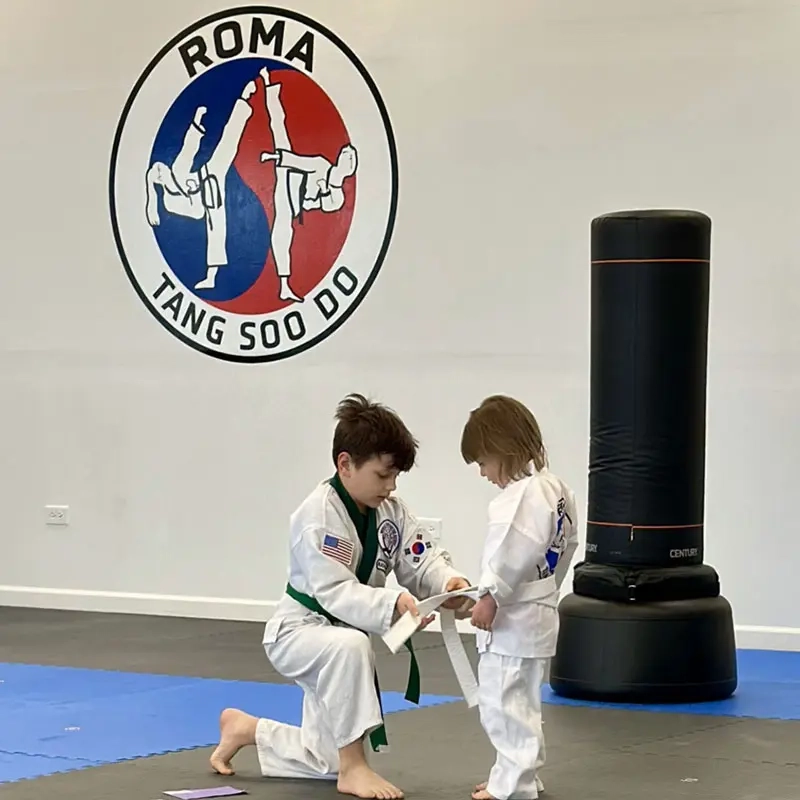 Young martial arts student helping another student learn discipline, respect, and self defense awareness.